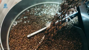 Freshly roasted coffee beans being discharged from a roasting chamber into a cooling tray.