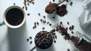 Beberapa gelas berisi kopi seduh, bubuk kopi, dan biji kopi sangrai tersusun berjejer.